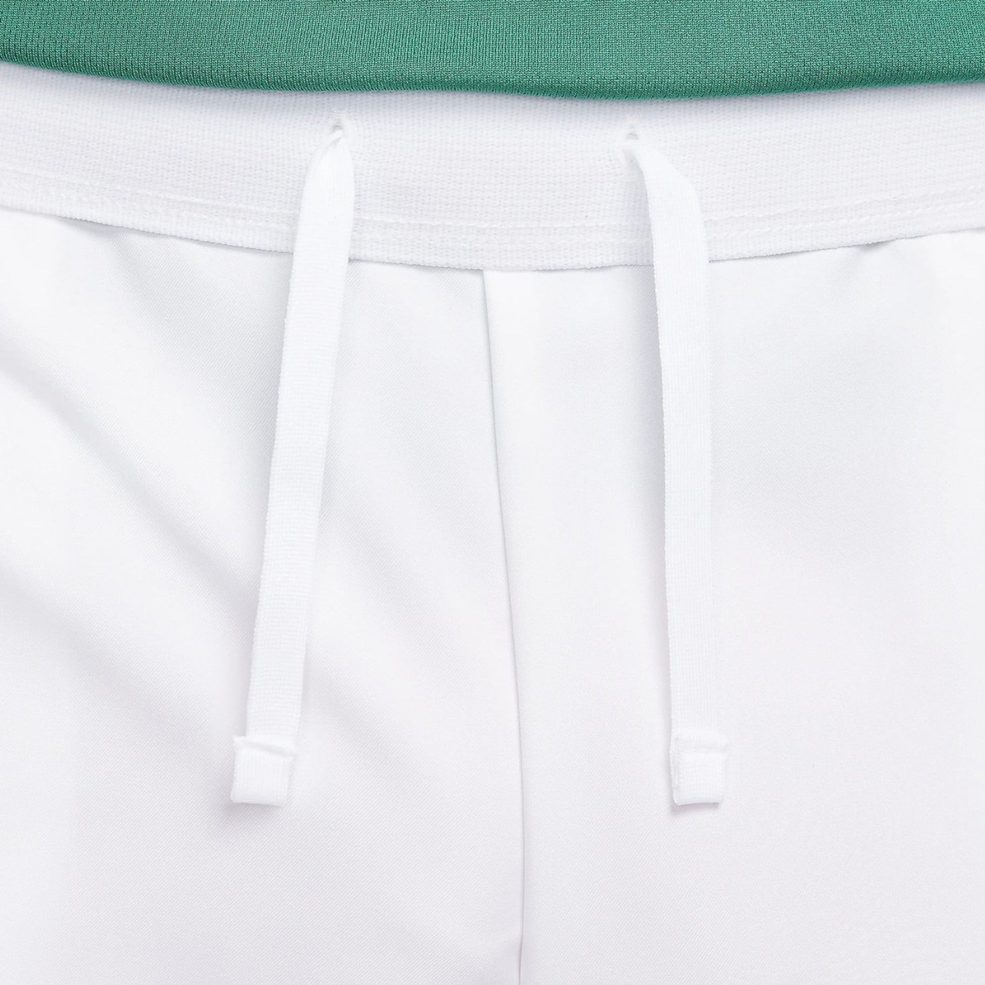 Close-up of white shorts with a green top on a light gray background