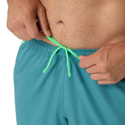 Teal shorts with green drawstring being adjusted by a person.
