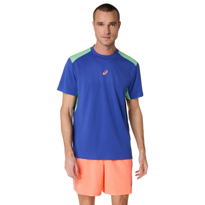 Man wearing a blue athletic shirt with green accents and orange shorts on a white background