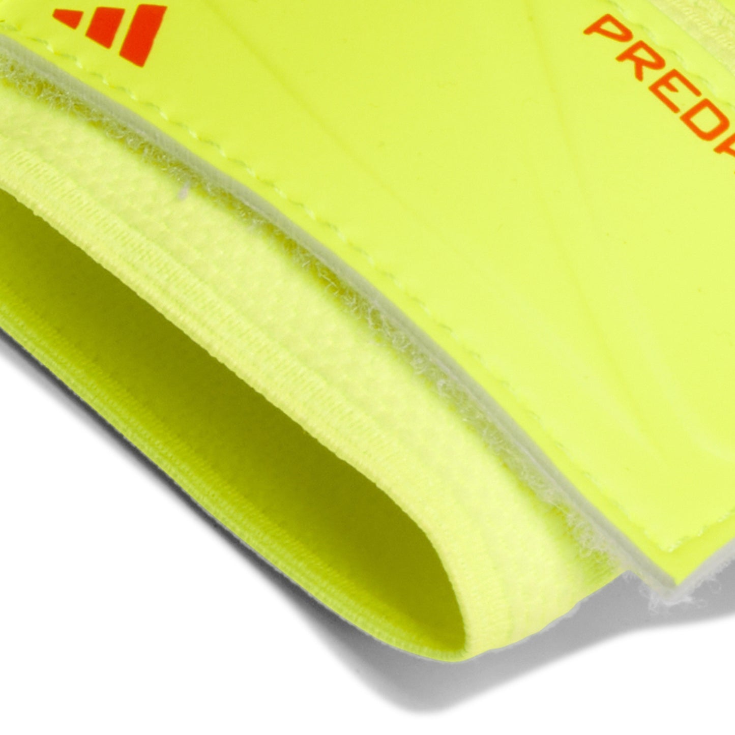Close-up of a bright yellow shin guard with Adidas logo and 'Predator' text on a white background