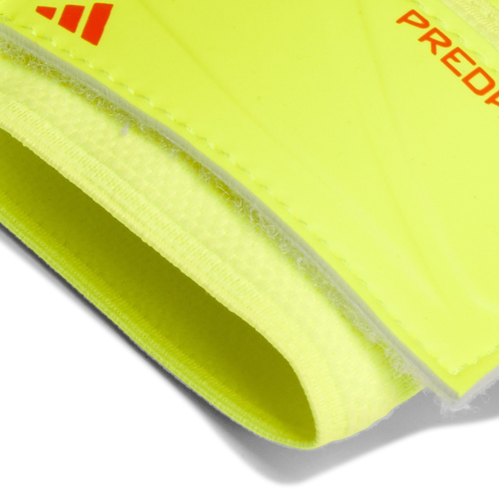 Close-up of a bright yellow shin guard with Adidas logo and 'Predator' text on a white background