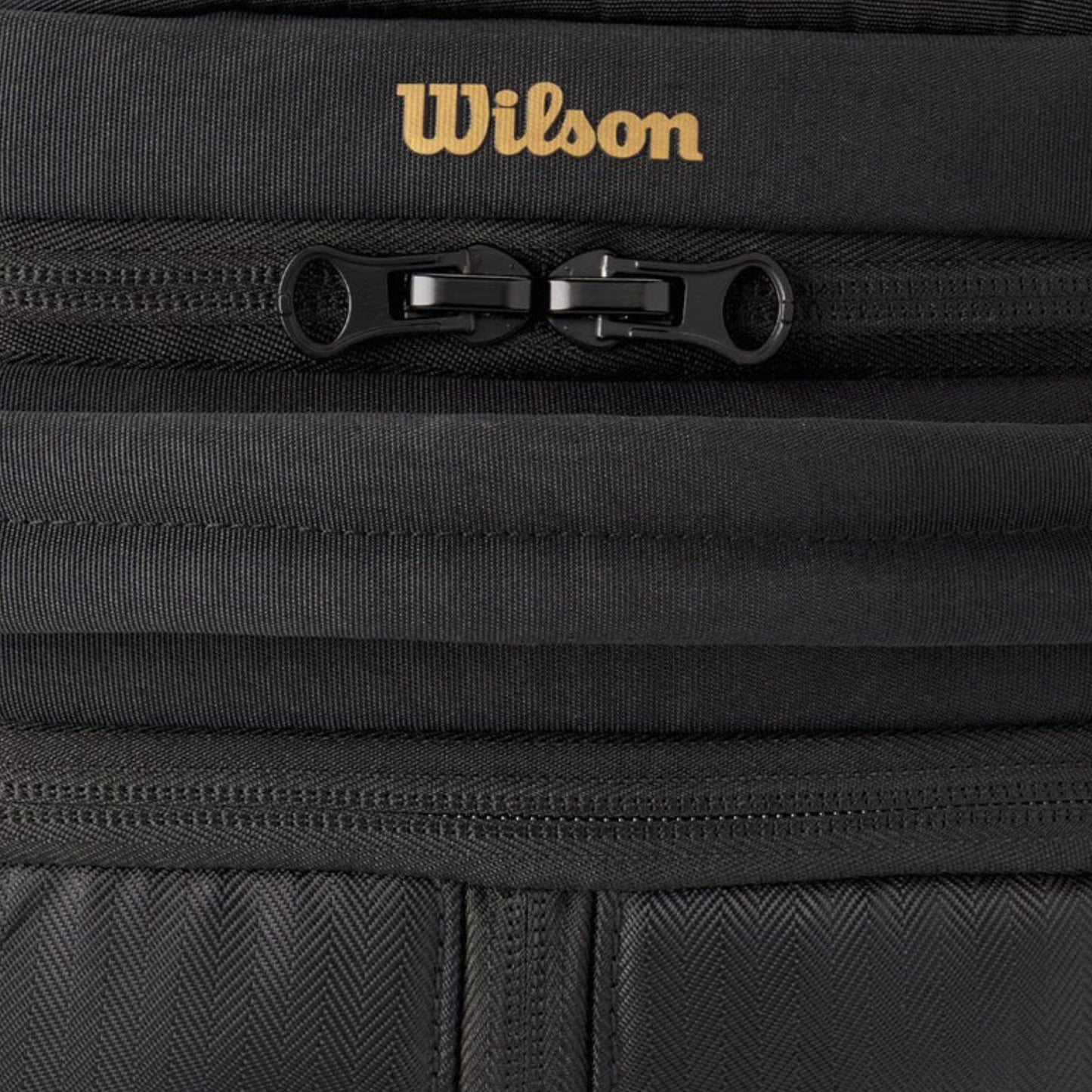 Close-up of a black bag with a gold Wilson logo on a black background