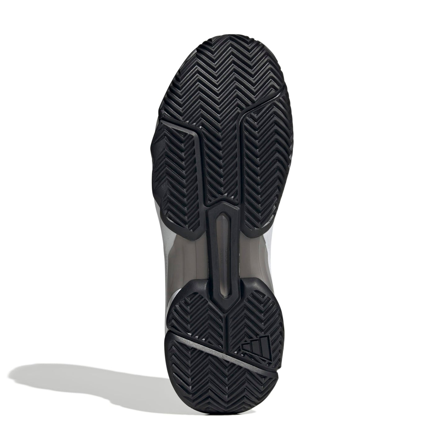 The outsole of a tennis shoe, showing a black herringbone tread pattern with a translucent gray midsole section, photographed on a white background with a soft shadow.