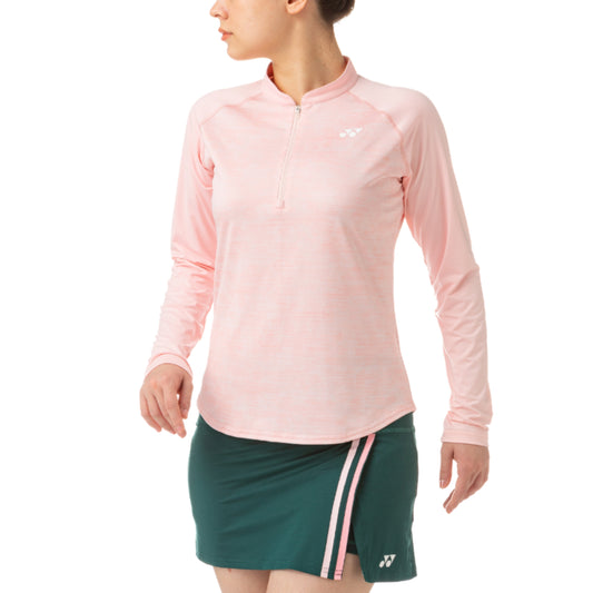 Person wearing a pink long-sleeve athletic Yonex top and green skirt with white stripes on a white background