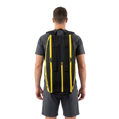 Person wearing a black Yonex tennis bag with yellow accents on a white background