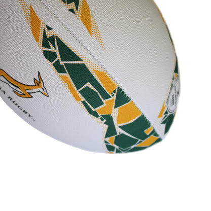 Close-up of a rugby ball with green and yellow patterns on a white background