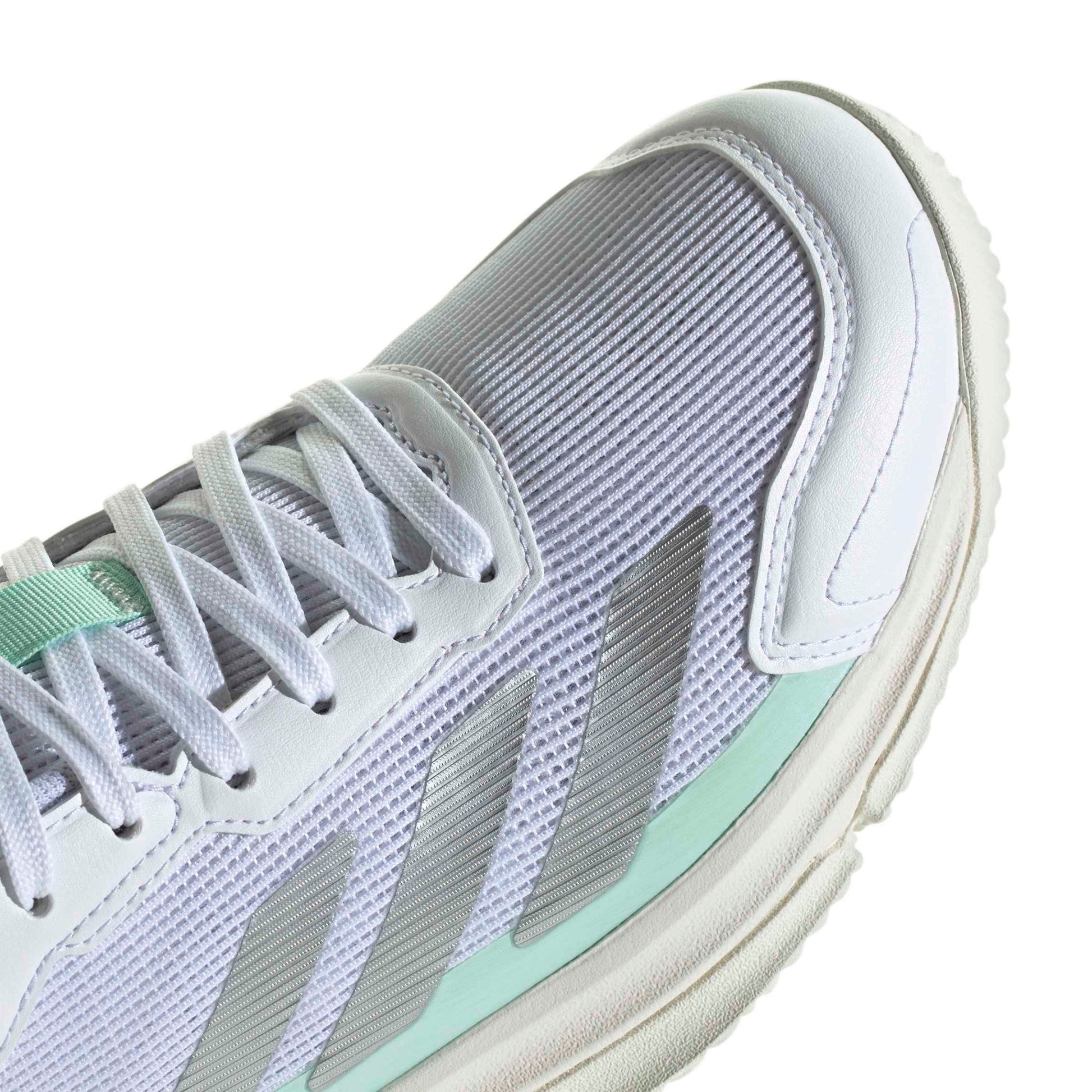 Close-up of a white and mint green athletic shoe showing the side panel, laces, and textured mesh upper.