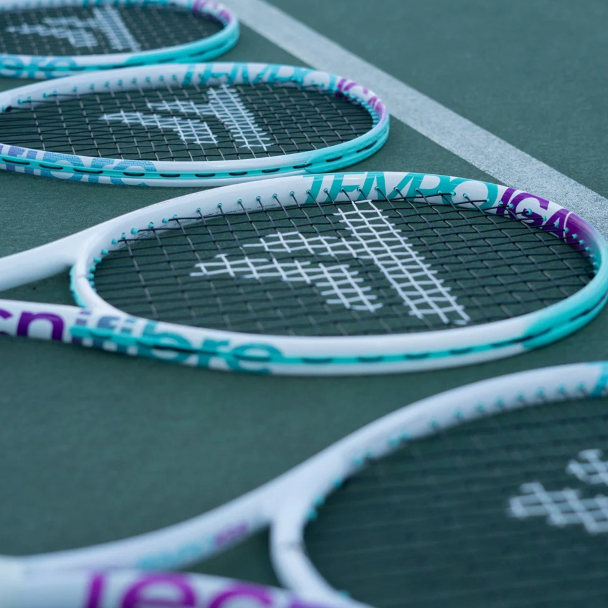 Close-up of tennis rackets with a brand logo on a green court surface