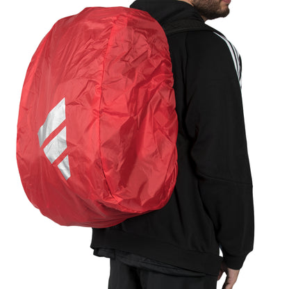 Person wearing a red backpack cover with a visible brand logo on a plain background