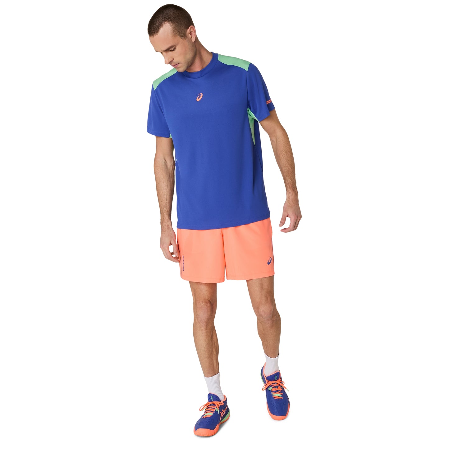 Man wearing a blue athletic shirt and orange shorts on a white background