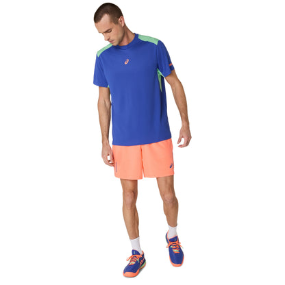 Man wearing a blue athletic shirt and orange shorts on a white background