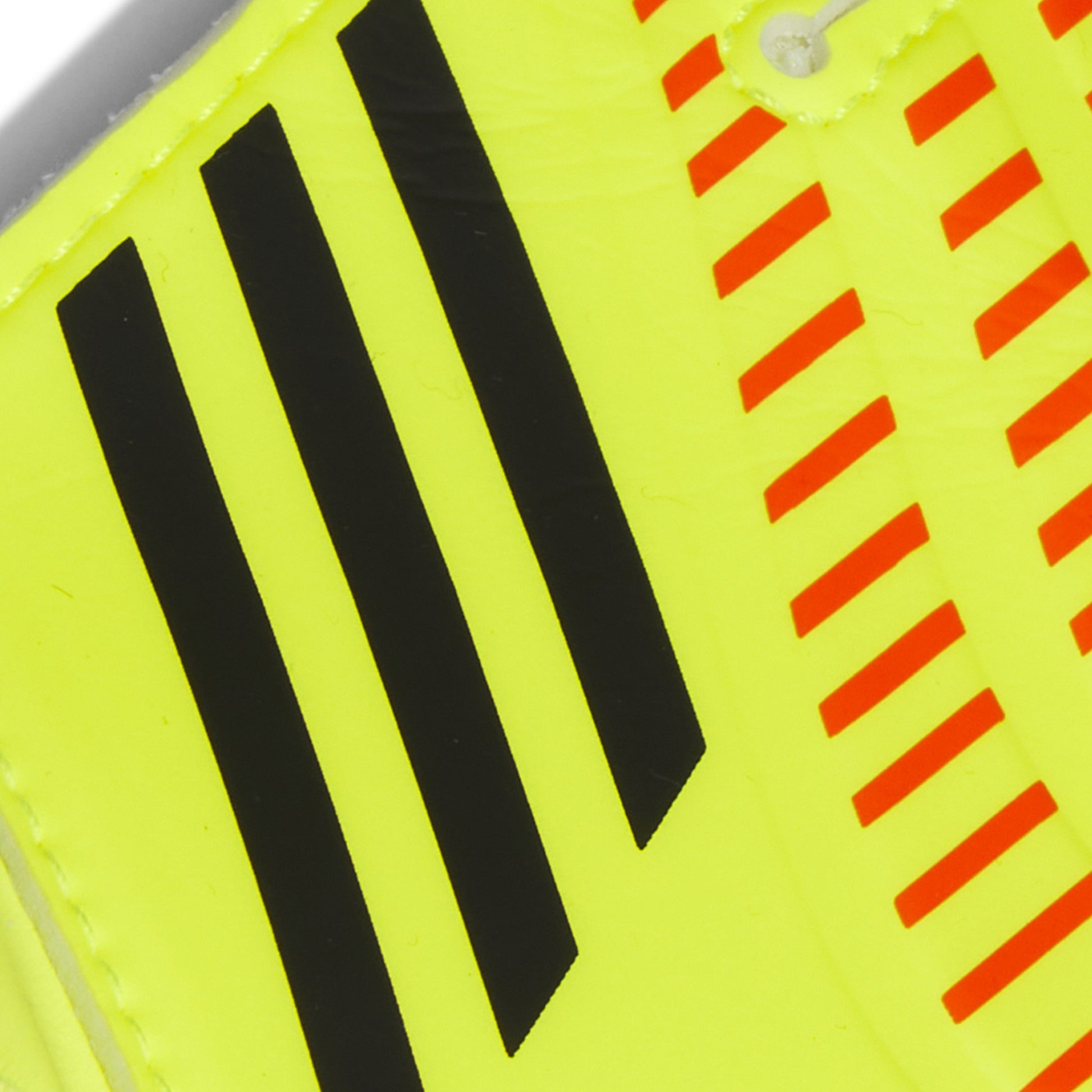 Close-up of a sports shoe with black stripes and red warning stripes on a yellow background