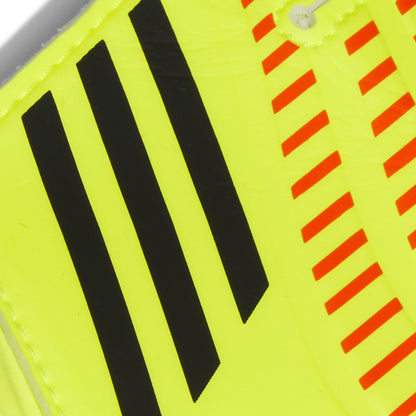 Close-up of a sports shoe with black stripes and red warning stripes on a yellow background