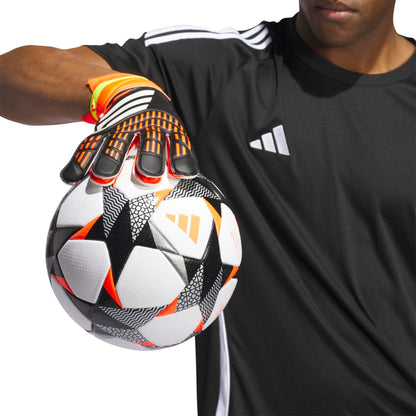 Person holding a soccer ball with a black and orange glove
