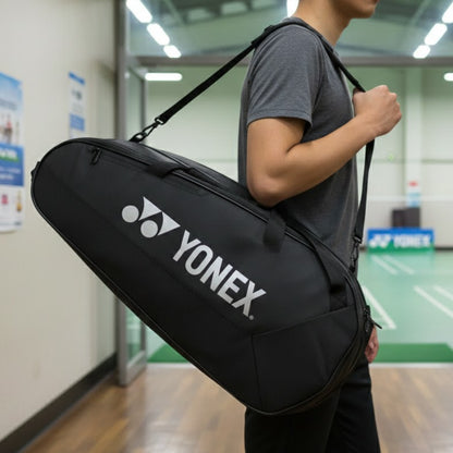 Person holding a Yonex bag in an indoor sports facility.