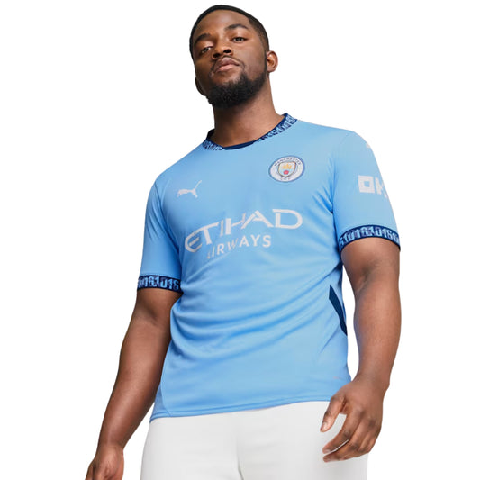 Man wearing a light blue Puma soccer jersey with branding on a white background