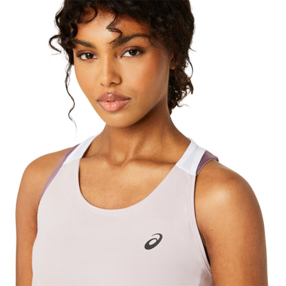 Woman wearing a light rose Asics athletic tank top with a brand logo on a white background