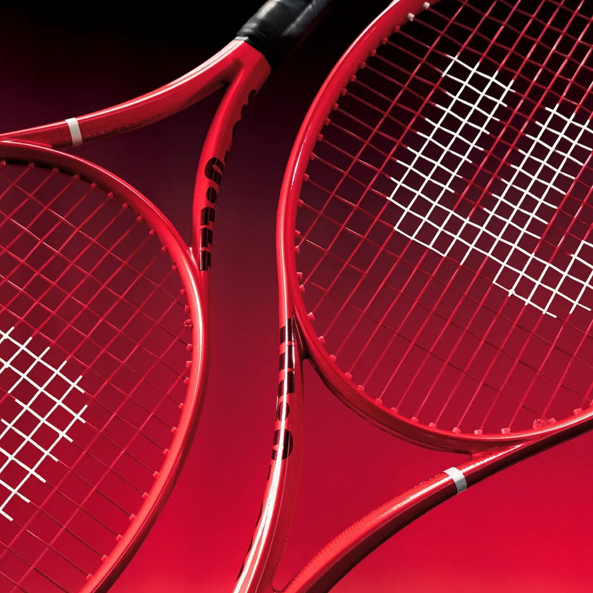 Two red Wilson tennis rackets shown in a close-up studio composition against a dark red background.