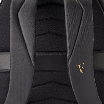 Close-up of a black backpack with a gold logo on the strap.