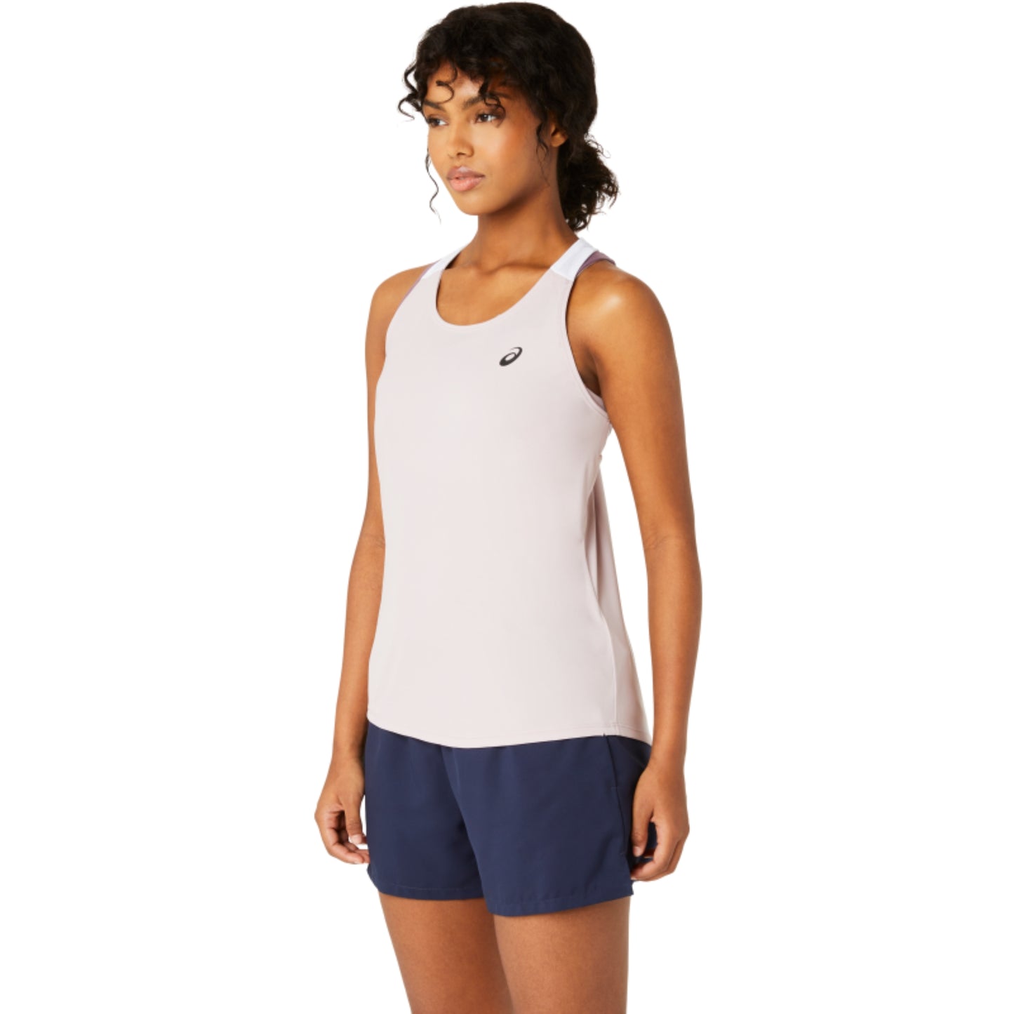 Woman wearing a light rose Asics tank top and navy shorts with a brand logo on a white background