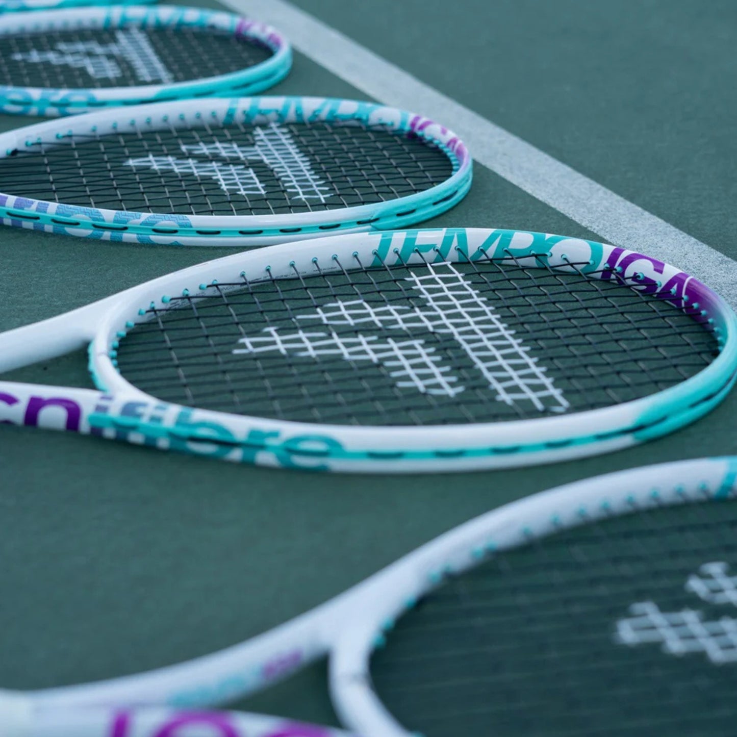Close-up of tennis rackets with a brand logo on a tennis court.