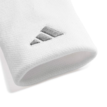 A close-up of a white wristband accessory featuring a dark gray embroidered Adidas logo.