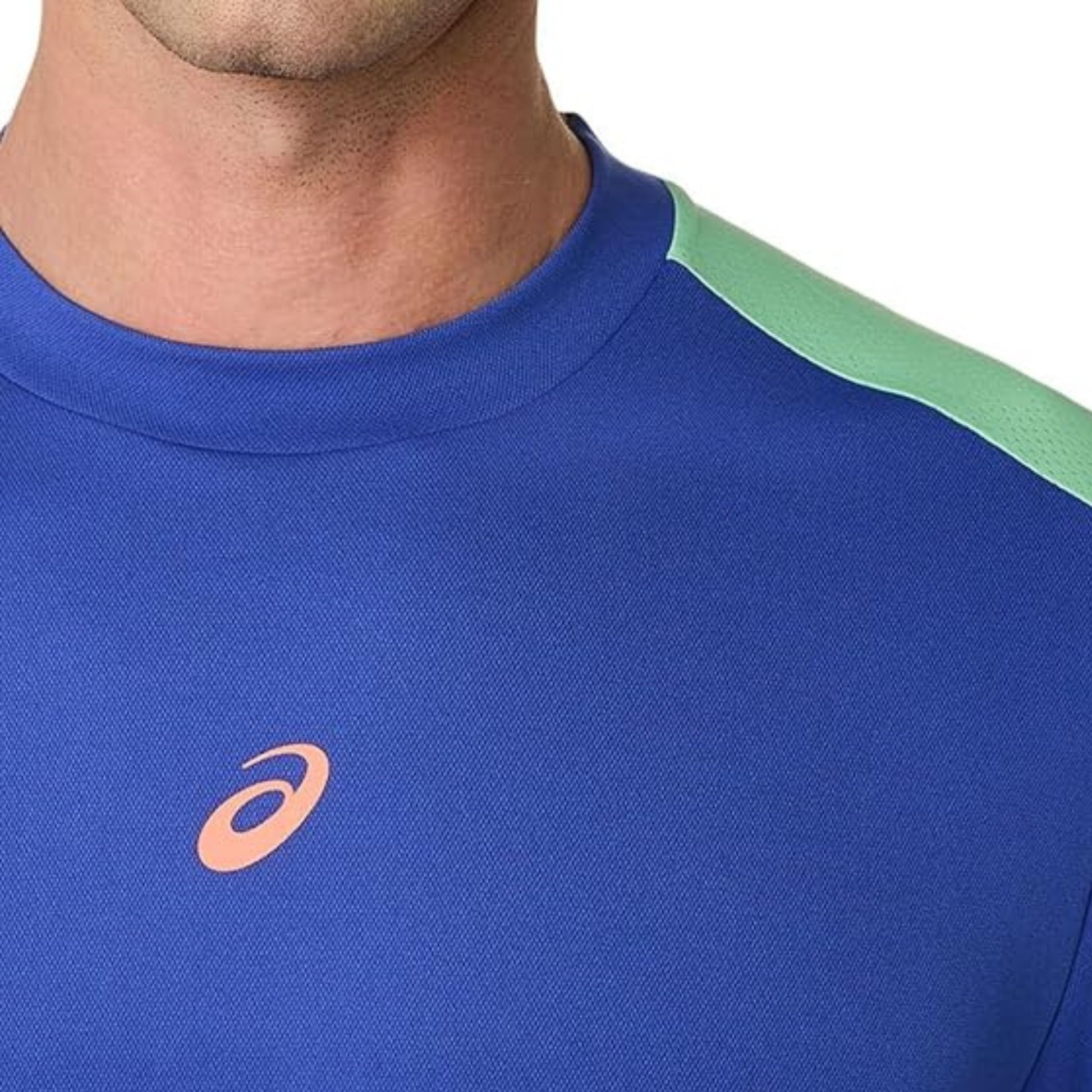 Blue athletic shirt with a logo on the chest, featuring green sleeves.