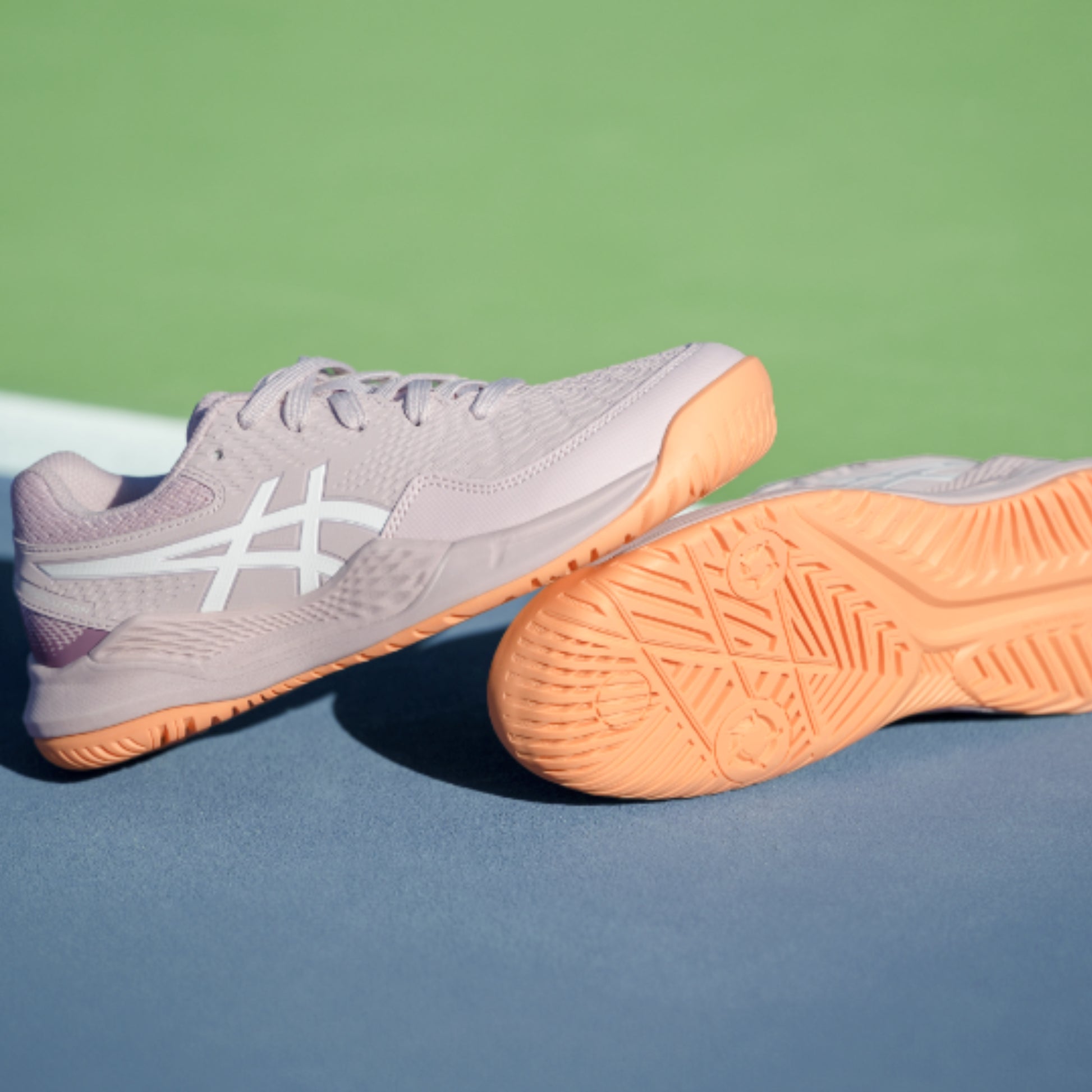 Asics Tennis shoes with orange soles on a tennis court
