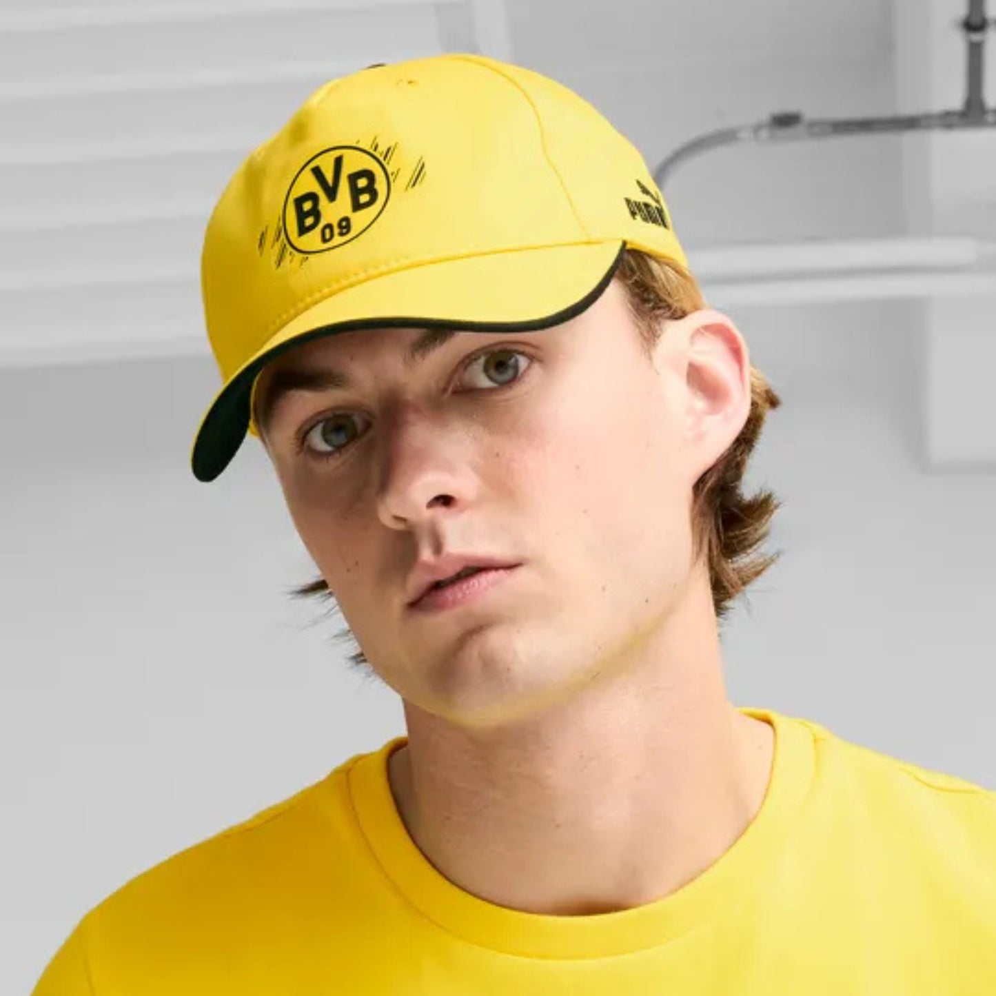 Person wearing a yellow cap with BVB logo against a plain background