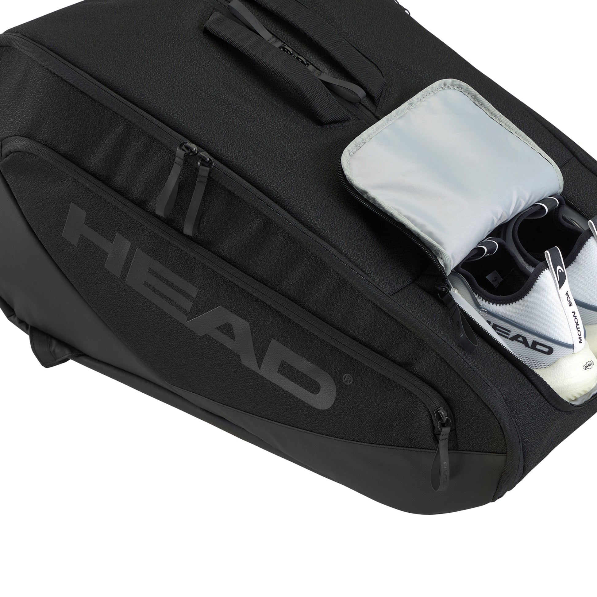 Black racket bag with visible 'HEAD' branding, open to reveal a shoe and other items.