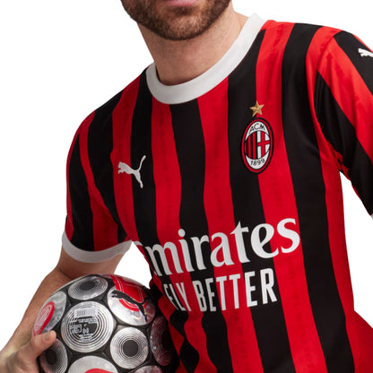 Person wearing a red and black striped Puma sports jersey with a logo, holding a soccer ball.