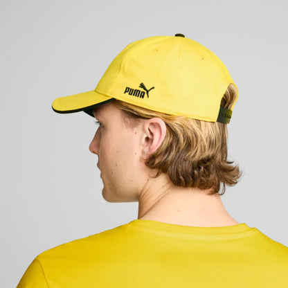 Person wearing a yellow Puma cap and shirt against a gray background